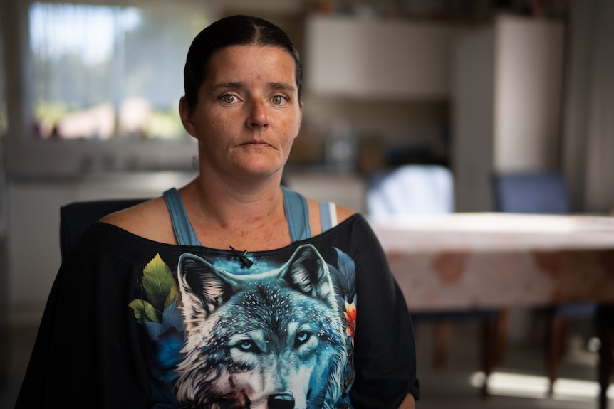 Woman in black t-shirt sits in kitchen for portrait