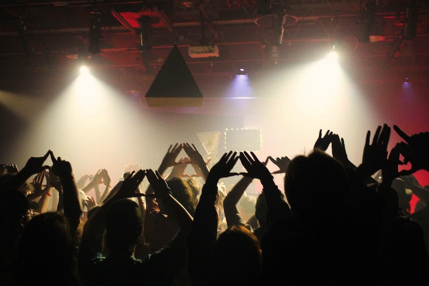 Crowd makes hand triangle gesture at rock band live performance.