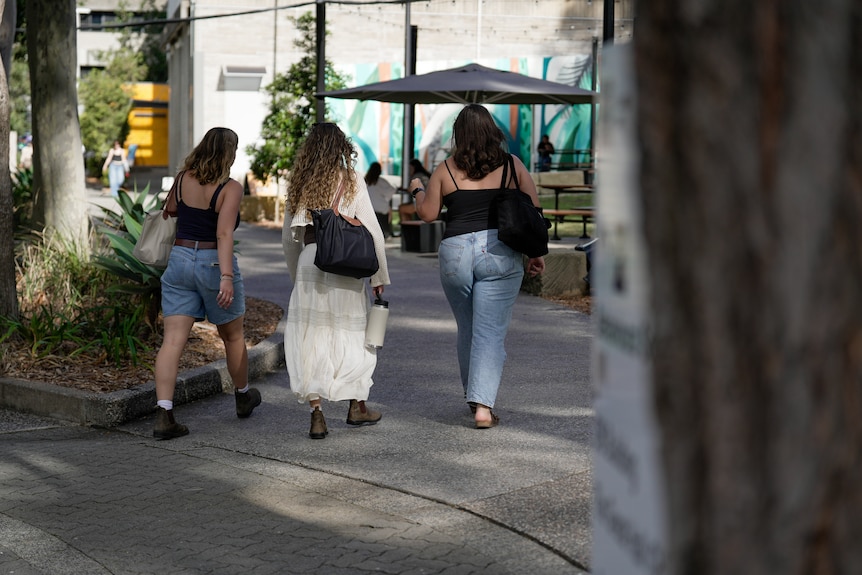 Three young women walking through a university campus.