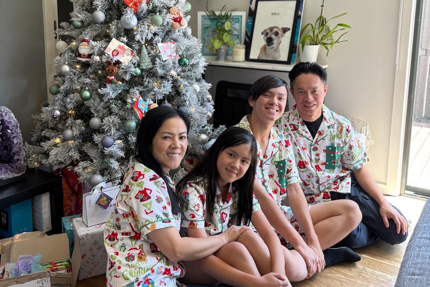 Cindy Mai with her husband and two kids in front of the Christmas tree
