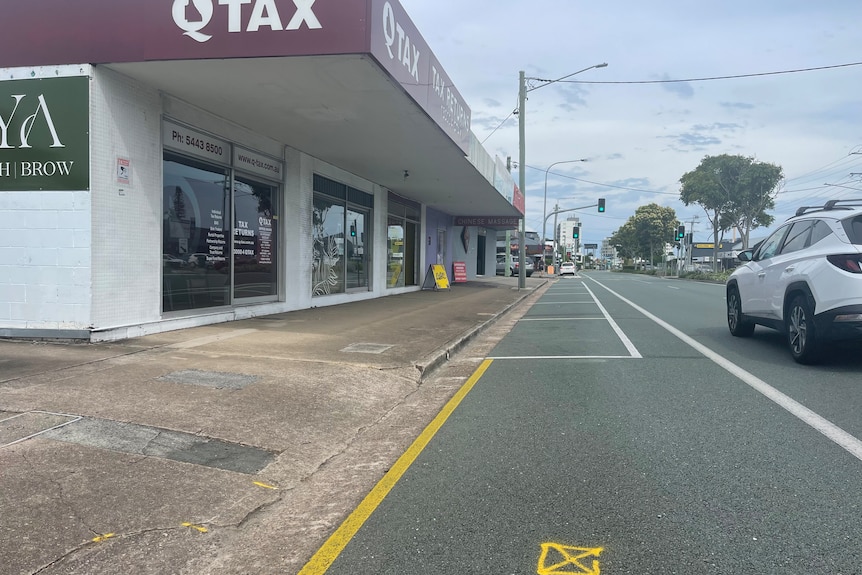 road and footpath in front of a suburban shopping strip.