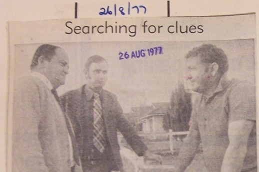 Old newspaper article photo of two detectives talking to a person in polo shirt.