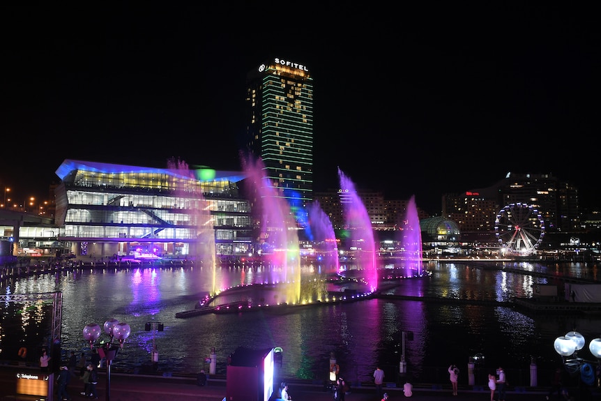 Darling Harbour lit up with purple lights during Vivid at night.