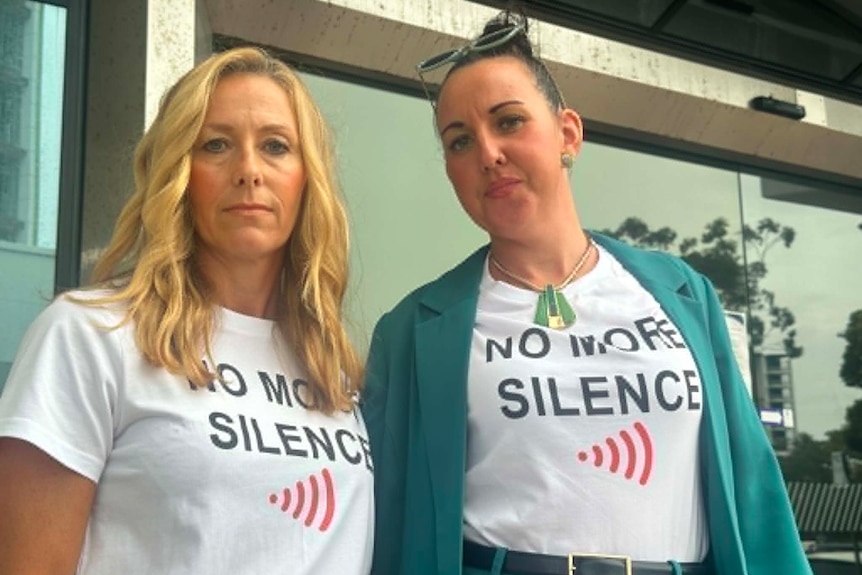 Two women standing outside court wearing shirt's which read no more silence