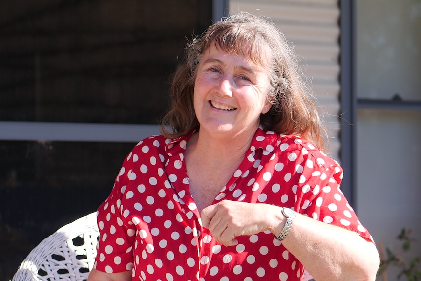Woman in white and red polkadot blouse smiling at camera.