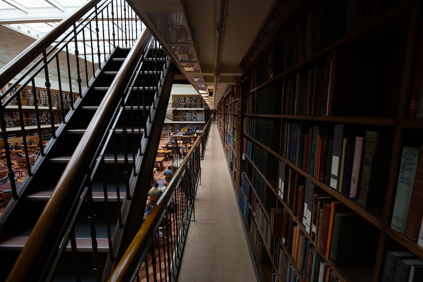 A dramatic shot of a staircase and rows of bookshelves inside the State Library of NSW