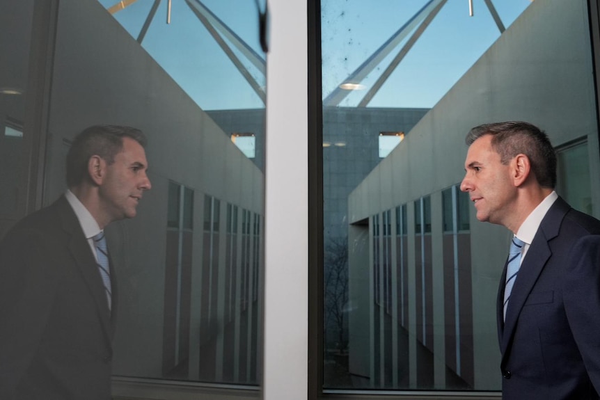 Jim Chalmers is reflected in a mirror