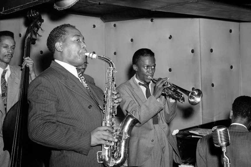 A bop ensemble performing on-stage featuring Charlie Parker on sax and Miles Davis on trumpet