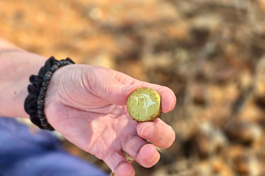 A woman's hand holding a bottle top.