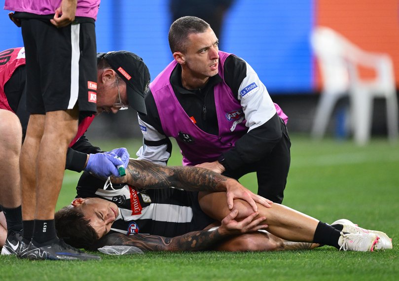 Jamie Elliott of the Magpies is attended to by trainers.