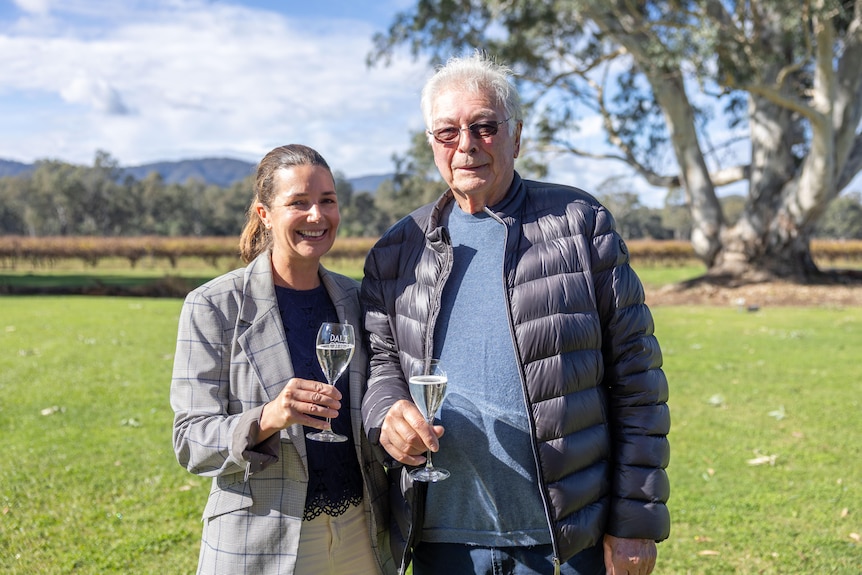 A woman and a man hold flutes of sparkling wine