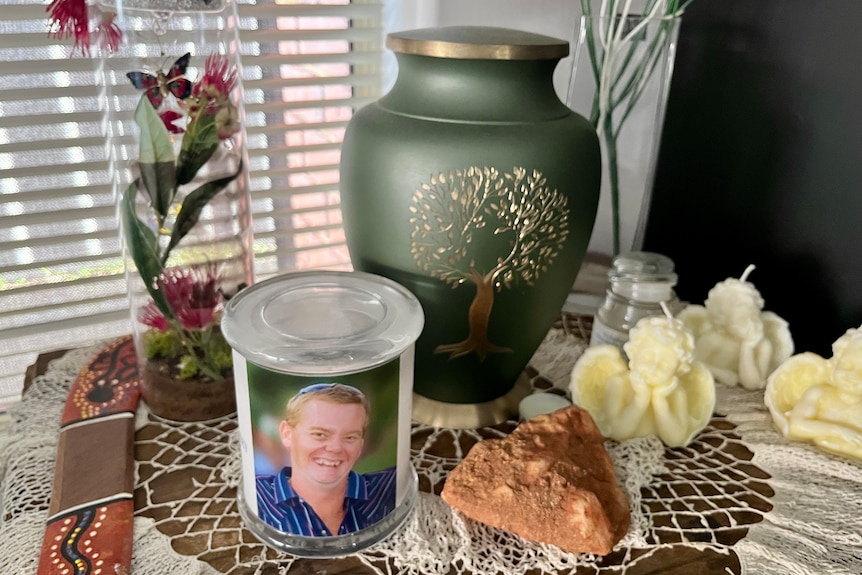 An urn with ashes near a photo of a young man.
