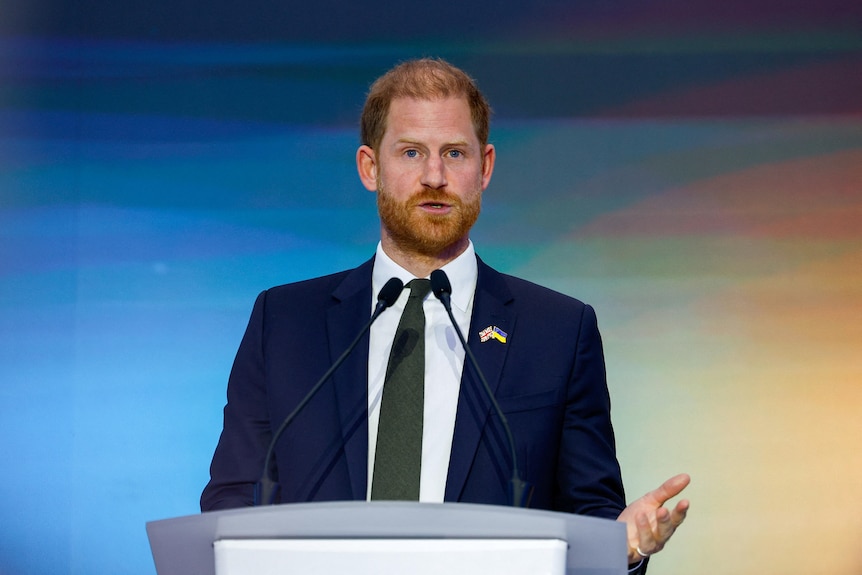 Britain's Prince Harry speaks at the Kyiv Security Forum, he is stood at a lectern behind a microphone