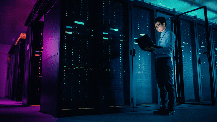 Man on his laptop standing next to data centres.