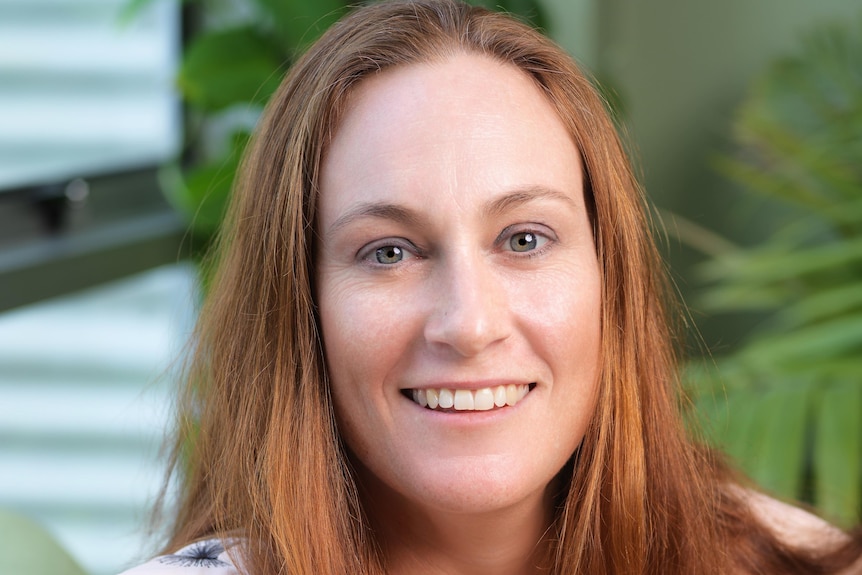 A red headed woman sits smiling at the camera