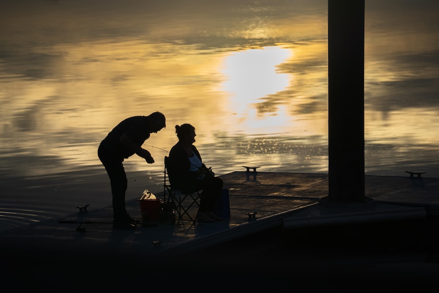 A couple fishing on a wharf at sunset in the vicinity of Port Augusta in SA.