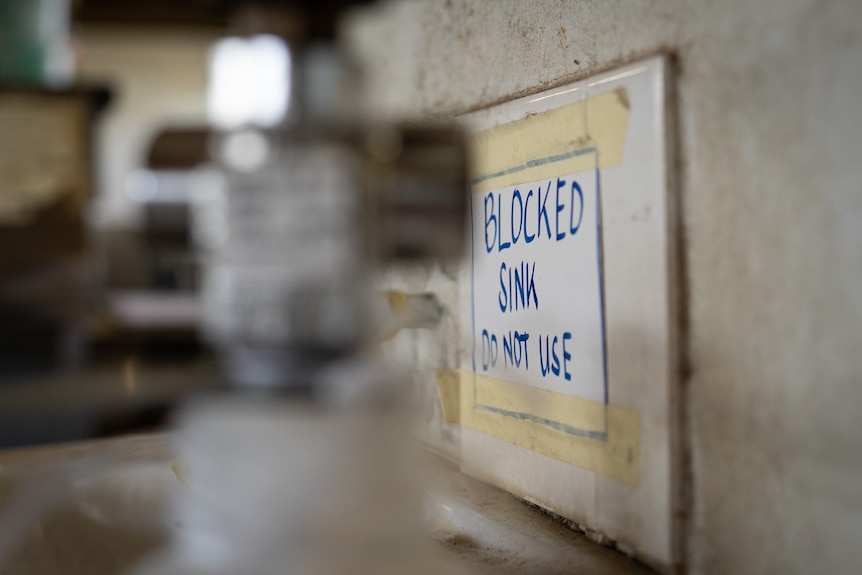 A sign saying the sink is blocked and not to use.
