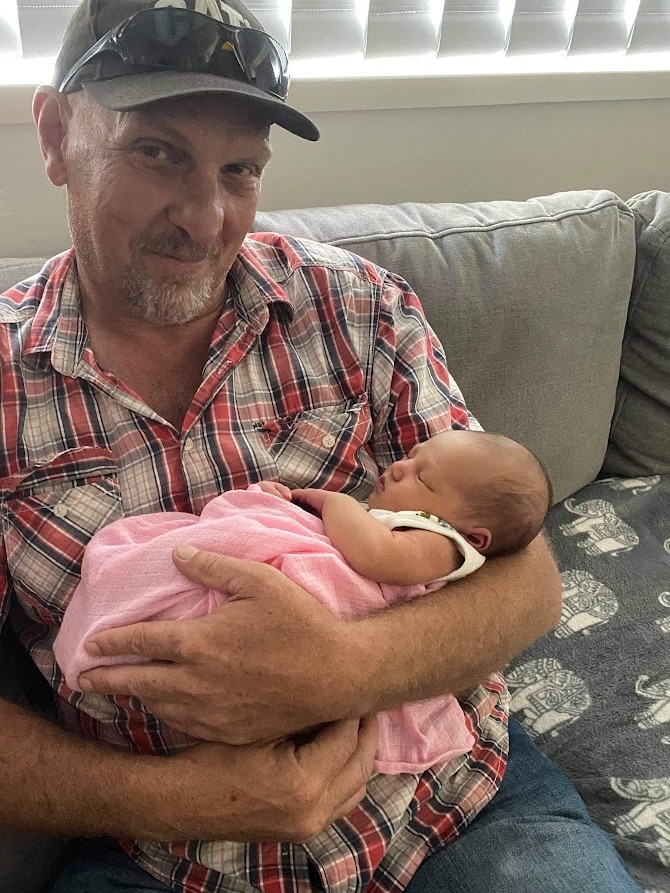 Grandad holding newborn, smiling, baby in blanket