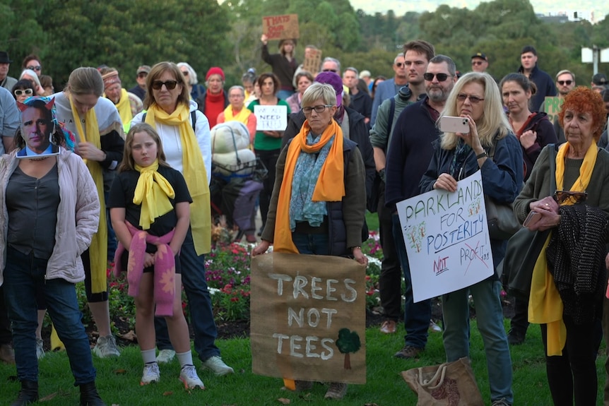 A group of people some with signs protesting against trees being cut down