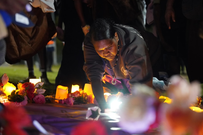 A woman writes on a poster by candlelight