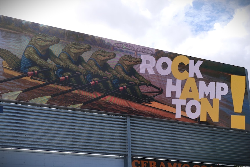 Cartoon crocodiles rowing on a billboard with the word 'CAN' highlighted in the word Rockhampton