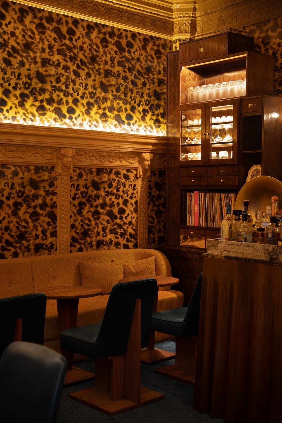 Interior of a stylish bar featuring animal-patterned wallpaper and elegant furnishings.