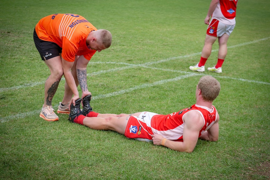 A runner helps stretch a players' calves.