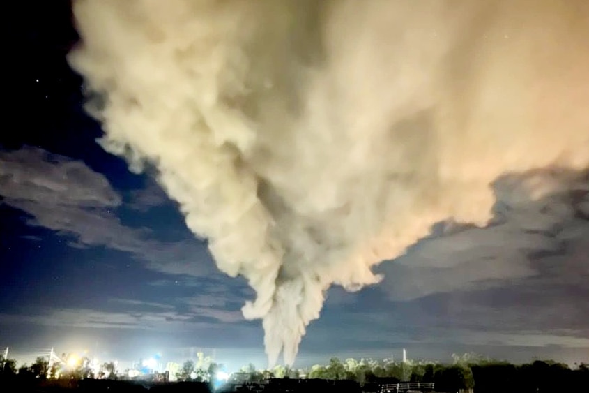 Smoke clouds rise into the night sky.