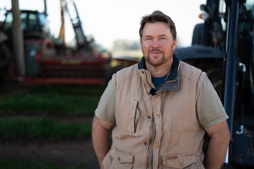 Man sits on front of tractor for portrait