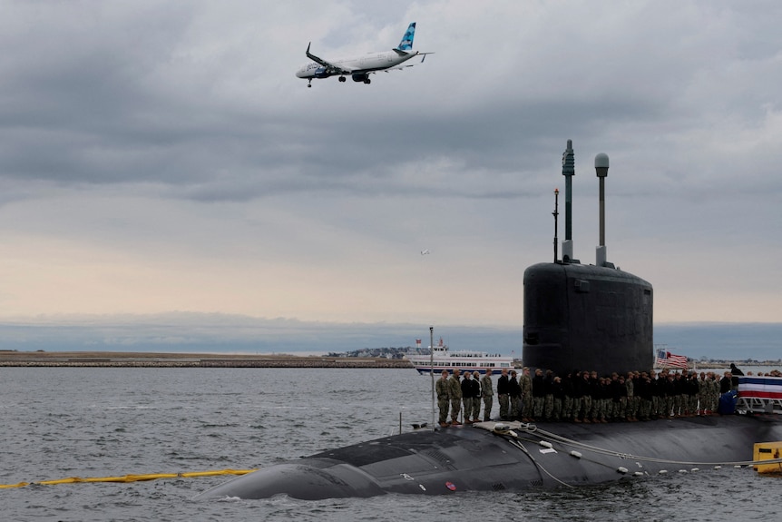 A crowd of people standing on a submarine.