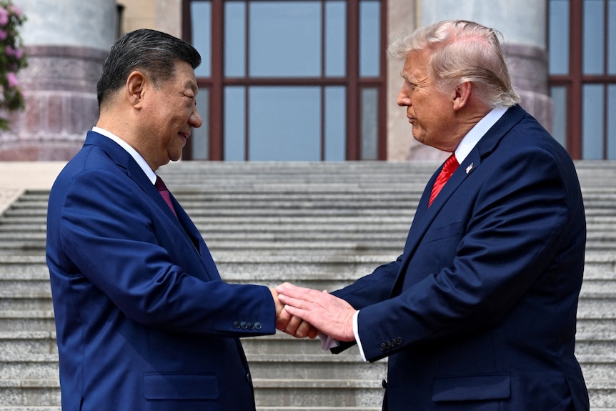 Xi and Trump shake hands on a set of stone stairs.