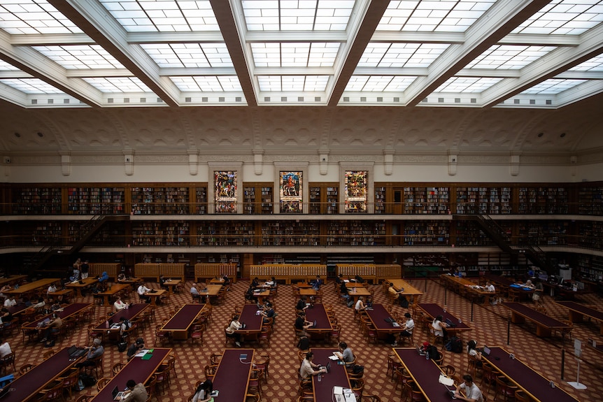 A large ornate room inside the State Library of NSW, featuring brown carpet and reading desks