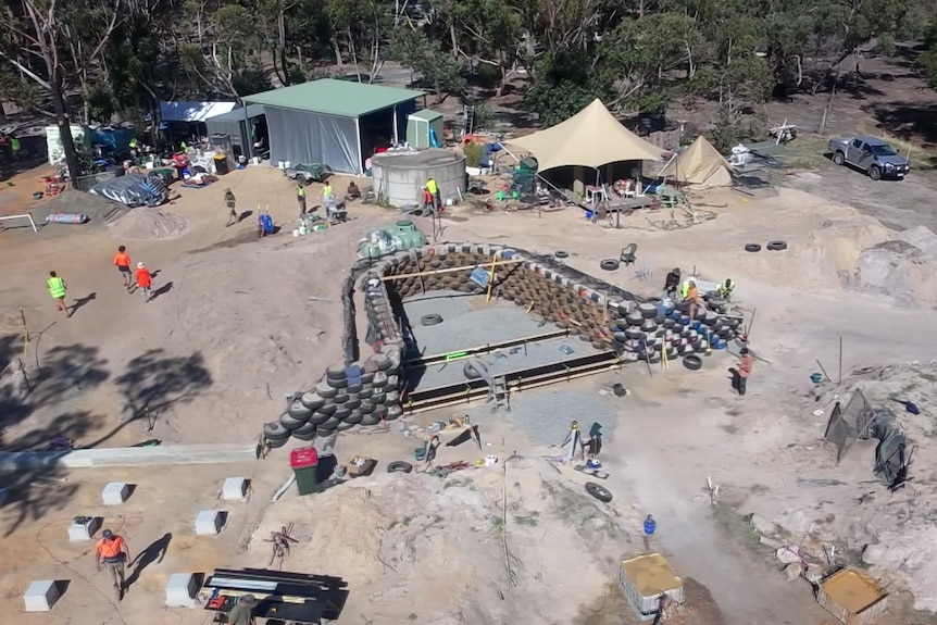 A drone shot of an Earthship built with tyres.