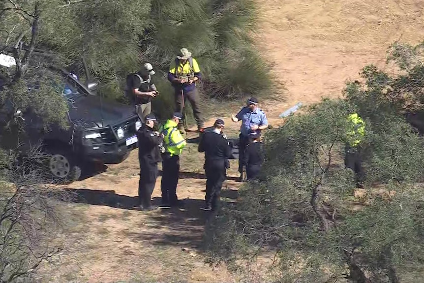An aerial shot of a number of police in scrubland.