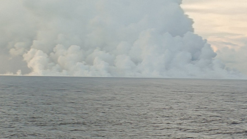 A volcano erupts under the ocean sending smoke and ash into the sky