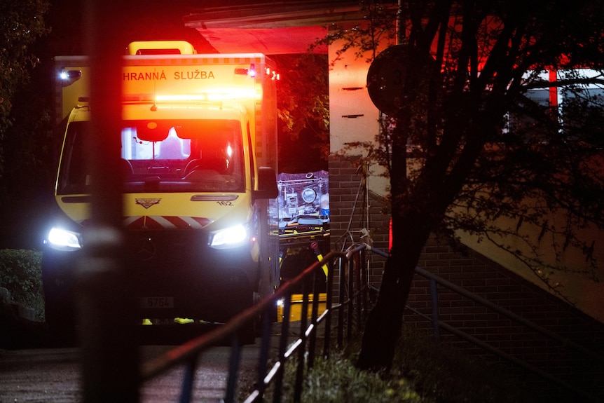 A patient in a stretcher is loaded into the back of a wheelchair in the evening.