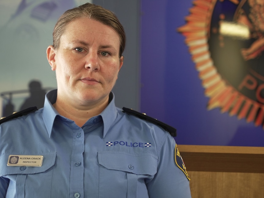 A female Tasmania Police officer in uniform stands at a podium addressing media