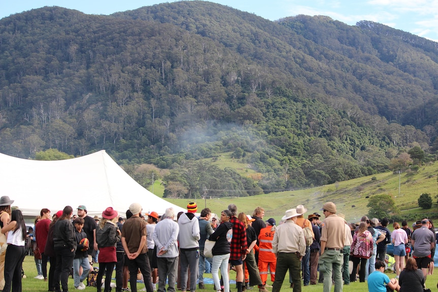 a group of people stand with a mountain in the background