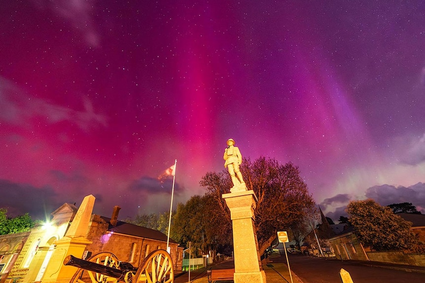 A statue of a male figure with a starry sky in the background.