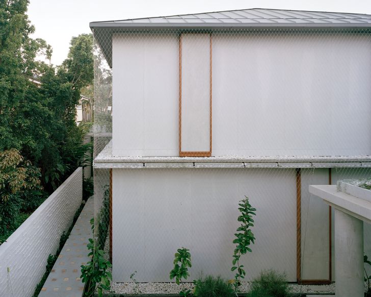 A continuous stainless-steel mesh wraps around the inner concrete block walls, supporting the growth of vines.