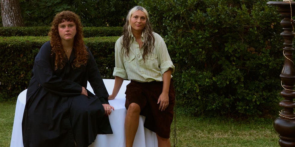 Two individuals seated at a table in an outdoor setting.
