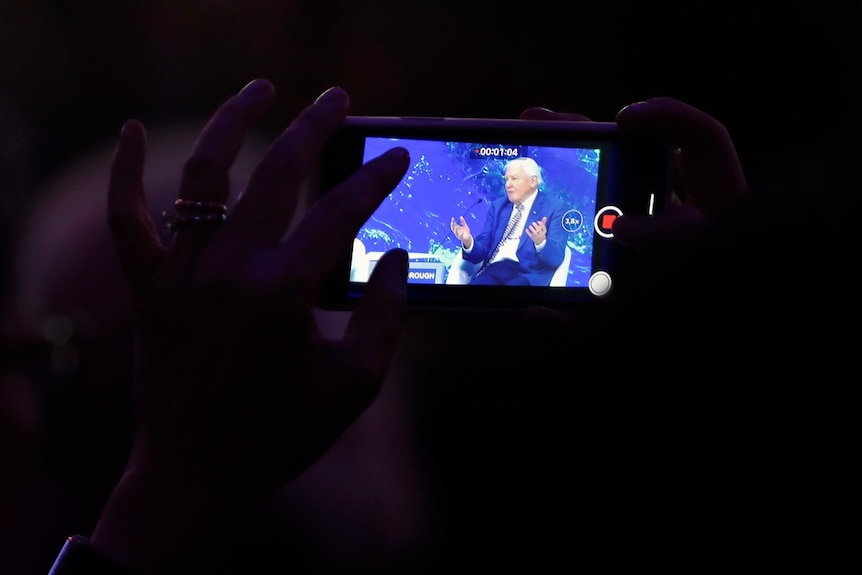 A smartphone screen, with a man visible on it.