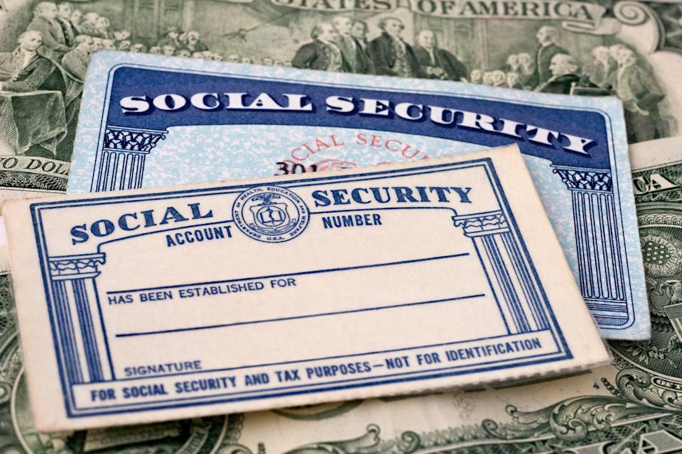 Social Security cards on top of dollar bills.