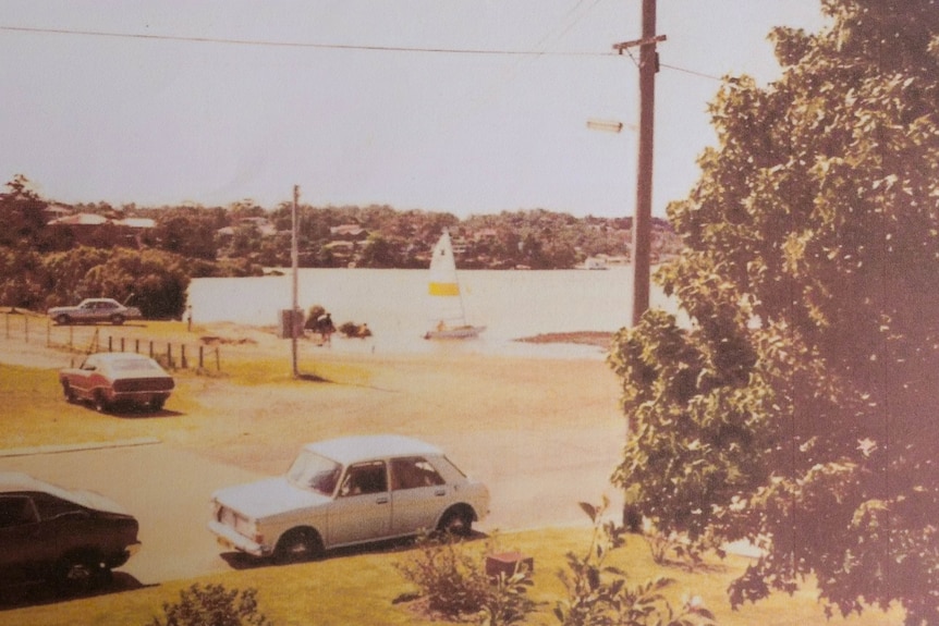 an old photo of a boat on a bay as seen from across a road