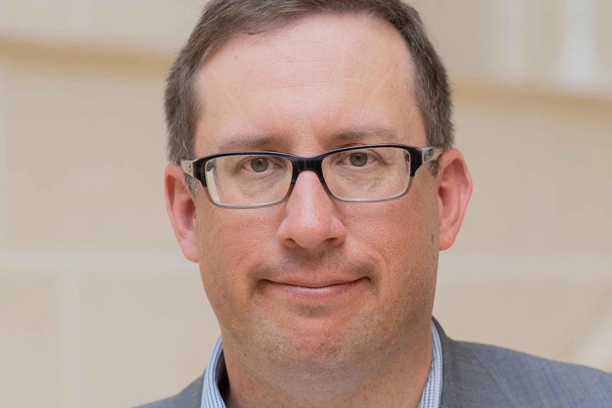 A man wearing glasses, smiling.