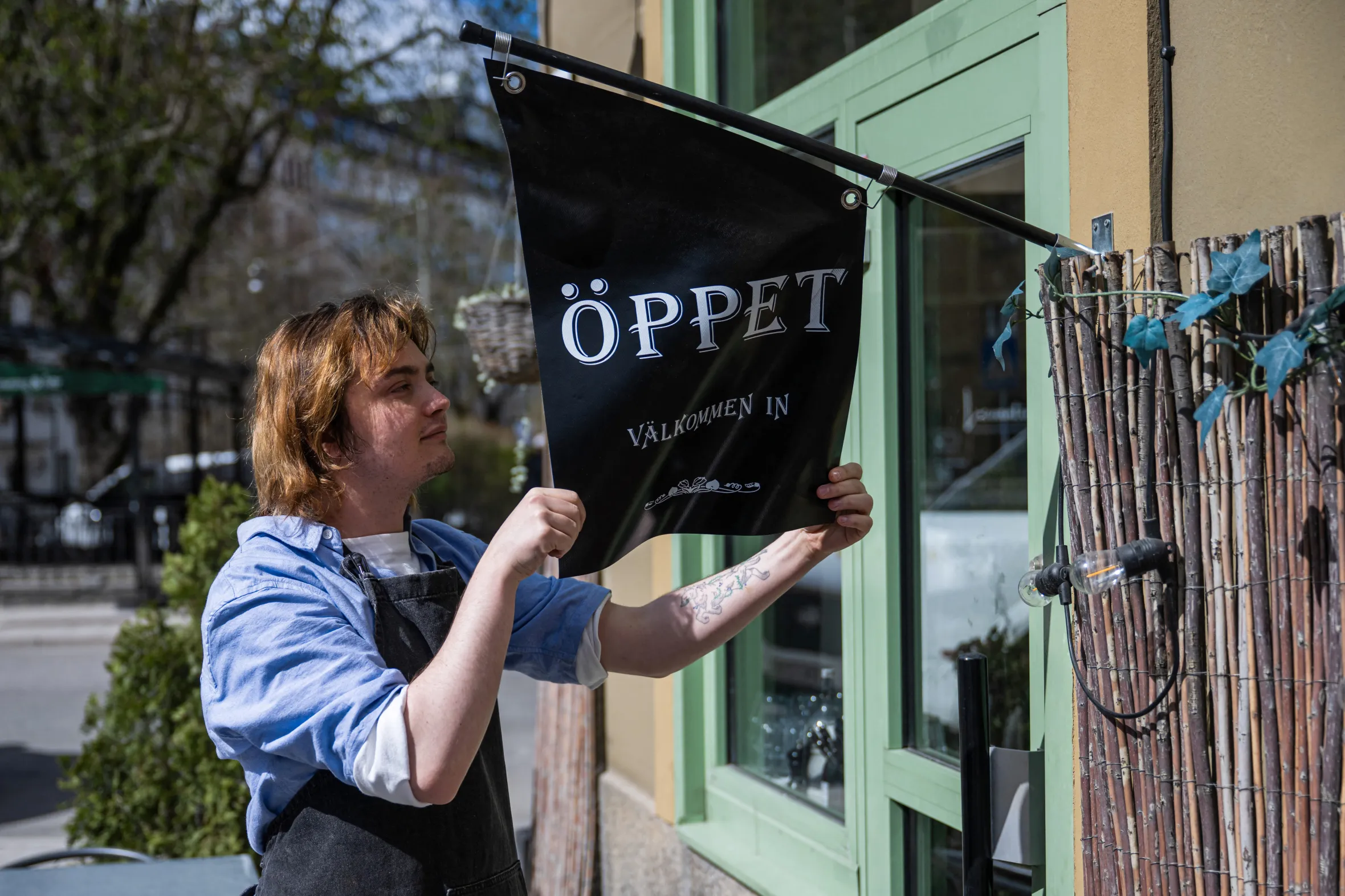 Kajetan Grzelczak, a barista, hangs an "Open" sign outside the Andon Café in Stockholm.