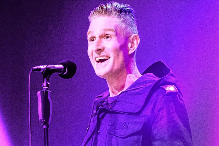 Wilsmiling behind microphone in pink light