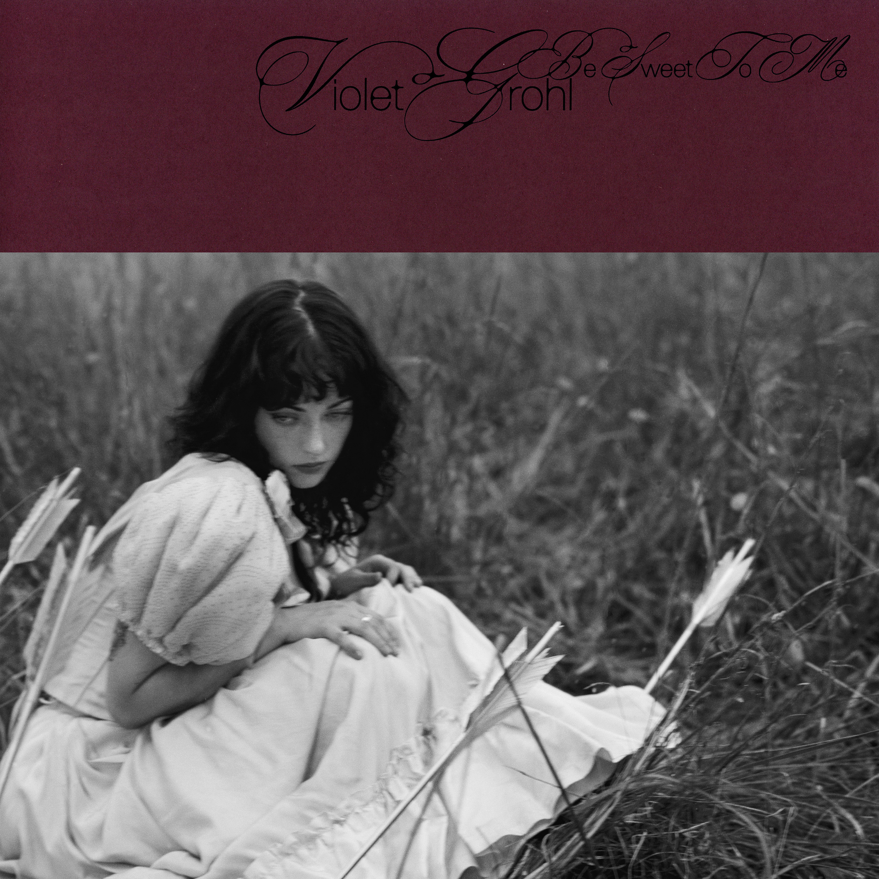 B&W phot of young woman in vintage rock crouched in field. Text reads: Violet Grohl Be Sweet To Me.