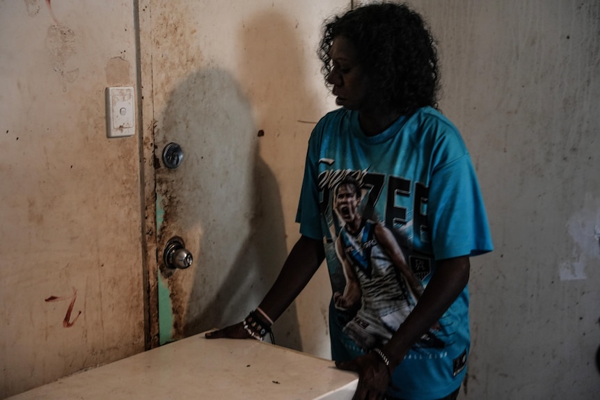 An Aboriginal woman lifting large white object in front of door