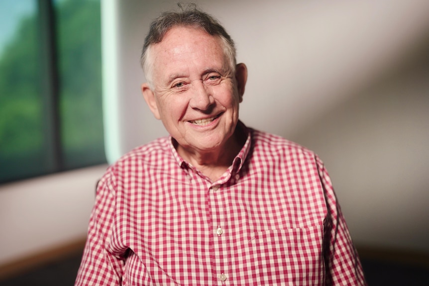 A man in a checked shirt, smiling at the camera.